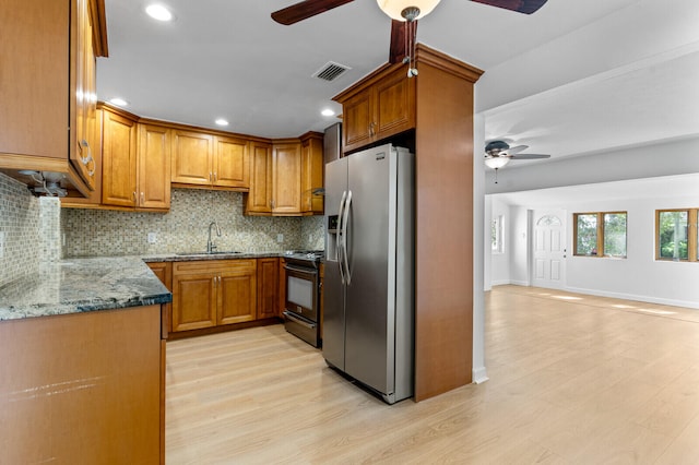 kitchen with sink, stainless steel fridge with ice dispenser, black electric range, light stone counters, and light wood-type flooring