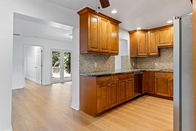 kitchen featuring decorative backsplash, dark stone countertops, appliances with stainless steel finishes, and light hardwood / wood-style floors