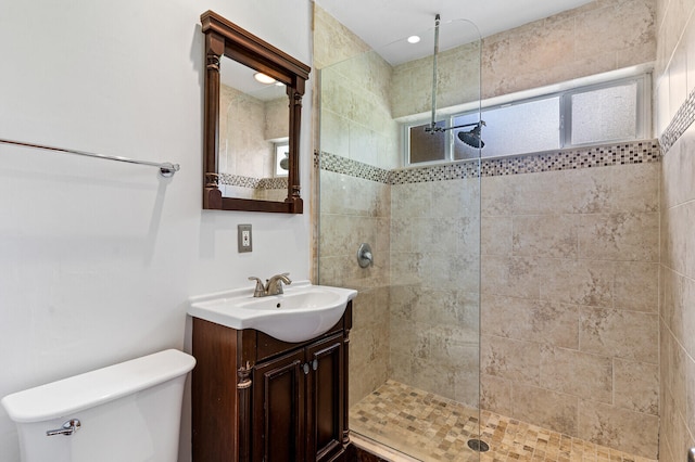 bathroom with a tile shower, vanity, and toilet