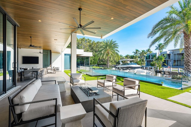 view of patio / terrace featuring ceiling fan and an outdoor living space with a fire pit