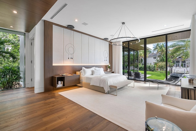 bedroom with access to outside, floor to ceiling windows, wood-type flooring, and a notable chandelier