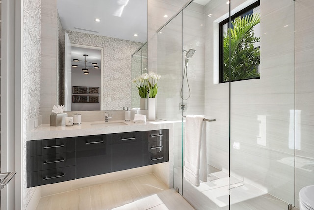 bathroom featuring tile patterned flooring, vanity, tile walls, and a shower with shower door