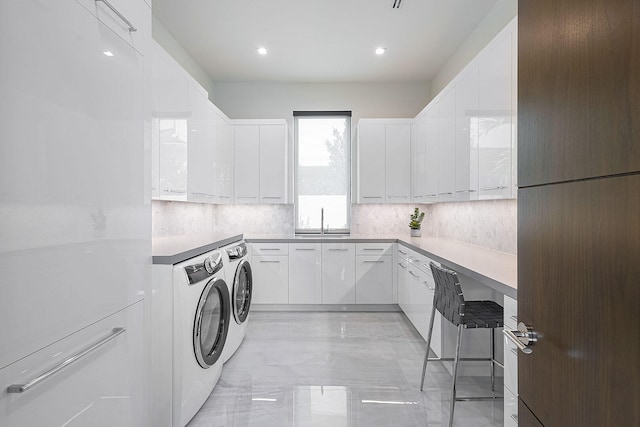 clothes washing area with cabinets, independent washer and dryer, and sink