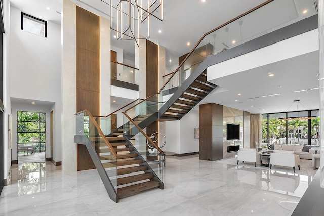 stairs featuring a fireplace, a towering ceiling, and a notable chandelier