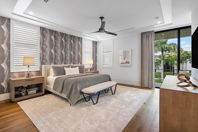 bedroom featuring hardwood / wood-style flooring, ceiling fan, access to exterior, and multiple windows