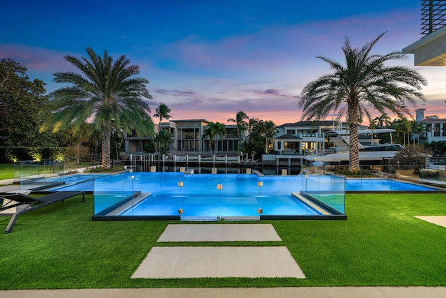 pool at dusk featuring a lawn