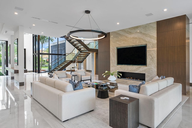 living room with floor to ceiling windows, tile walls, a high end fireplace, and a chandelier