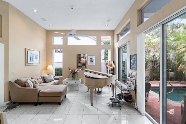 living room featuring plenty of natural light, ceiling fan, a towering ceiling, and light tile patterned floors