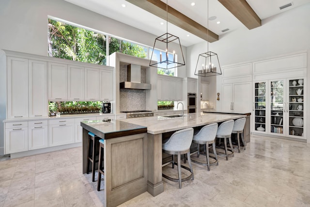 kitchen with beamed ceiling, a high ceiling, white cabinetry, and a spacious island