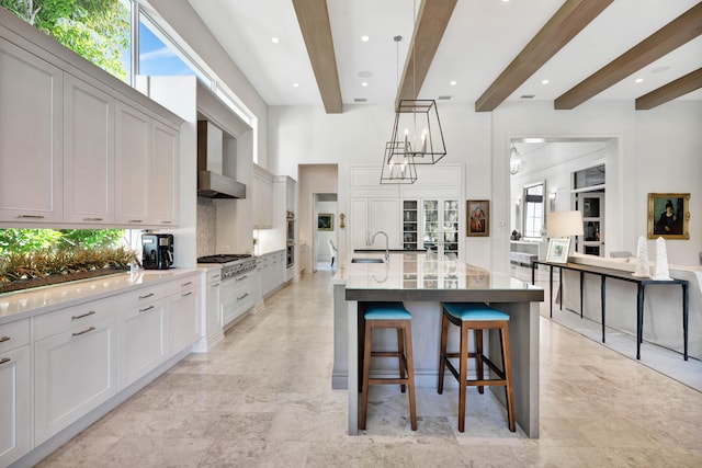 kitchen featuring beamed ceiling, a breakfast bar, a large island with sink, and tasteful backsplash