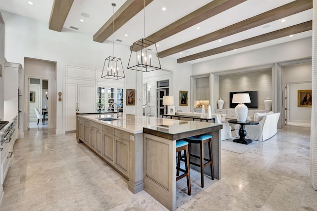 kitchen featuring light stone counters, beamed ceiling, a spacious island, decorative light fixtures, and a kitchen bar