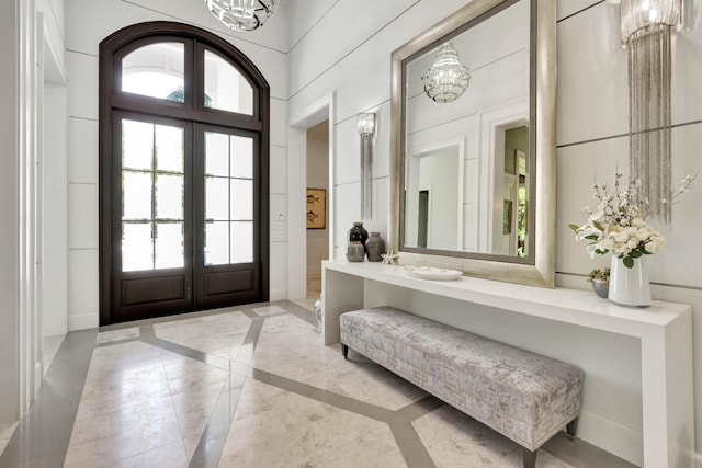 entrance foyer with a chandelier, french doors, and a towering ceiling