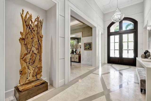 foyer entrance featuring french doors, ornamental molding, and an inviting chandelier