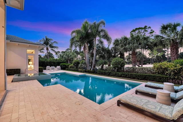 pool at dusk featuring a fire pit and a patio area