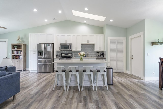 kitchen featuring a center island, a breakfast bar, white cabinets, and appliances with stainless steel finishes