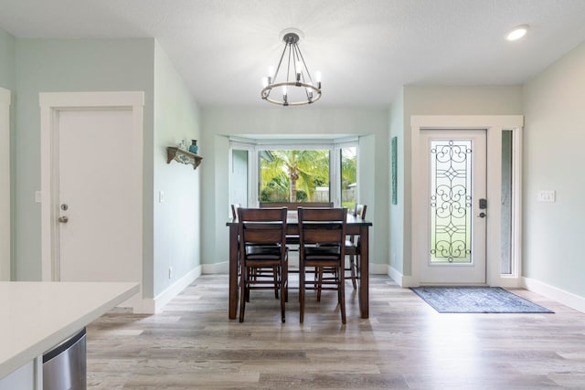 dining room with a textured ceiling, light hardwood / wood-style flooring, and an inviting chandelier