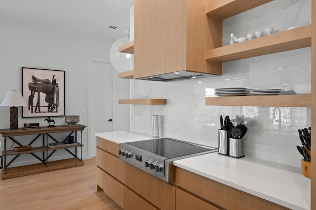 kitchen with stovetop, light hardwood / wood-style floors, and tasteful backsplash