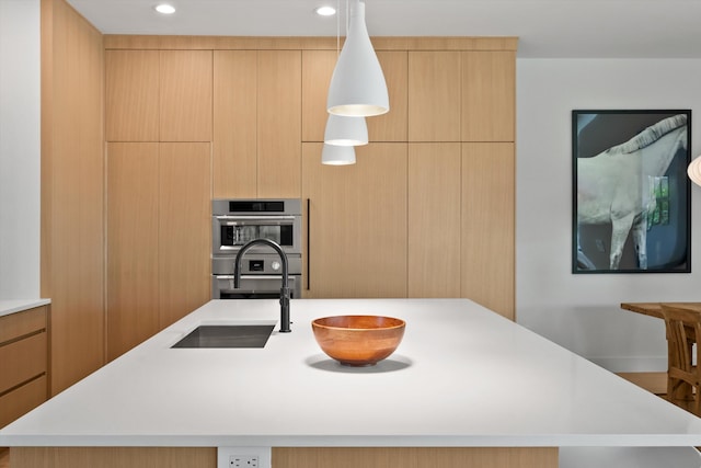 kitchen with light brown cabinets, a center island with sink, double oven, and sink