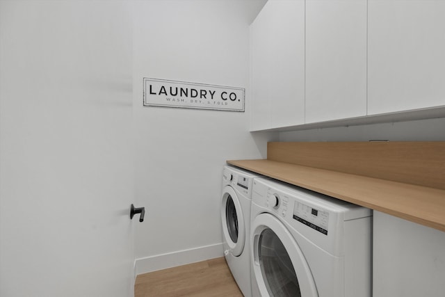 washroom with cabinets, light wood-type flooring, and washer and dryer