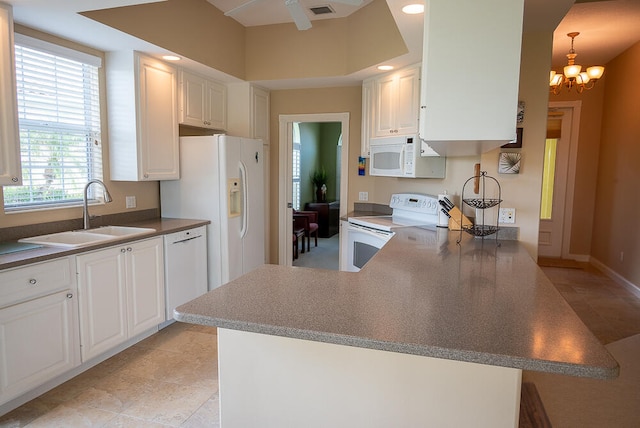 kitchen featuring a chandelier, a peninsula, white appliances, a sink, and white cabinets