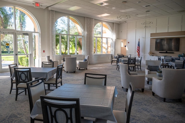 dining space with a towering ceiling, carpet, a decorative wall, and a wealth of natural light