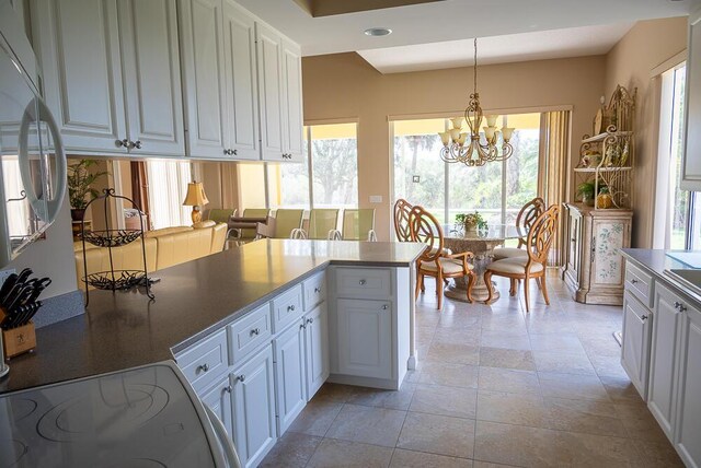 kitchen with white cabinets, range with electric stovetop, hanging light fixtures, a notable chandelier, and recessed lighting