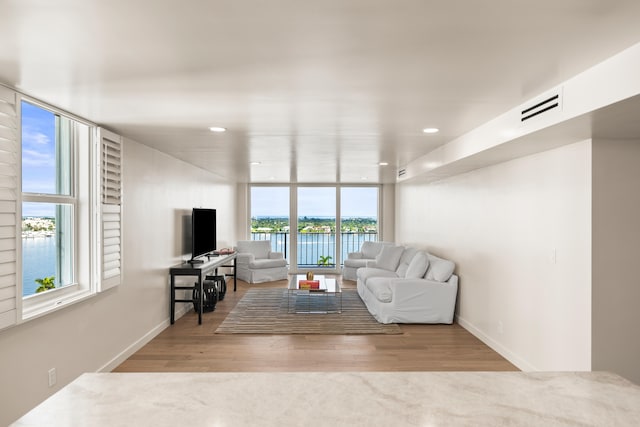 living room with a water view, floor to ceiling windows, and light hardwood / wood-style floors