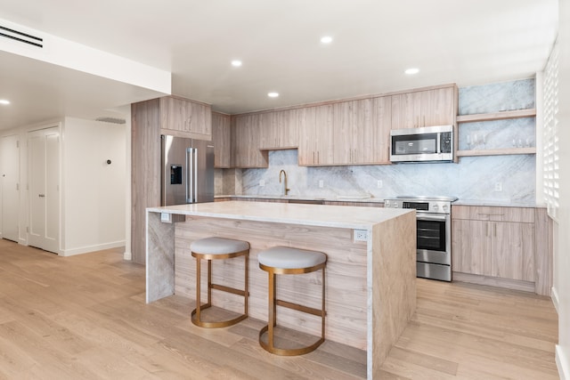 kitchen featuring light wood-type flooring, a breakfast bar area, a center island, and appliances with stainless steel finishes