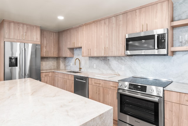 kitchen with appliances with stainless steel finishes, light brown cabinetry, sink, decorative backsplash, and light stone countertops