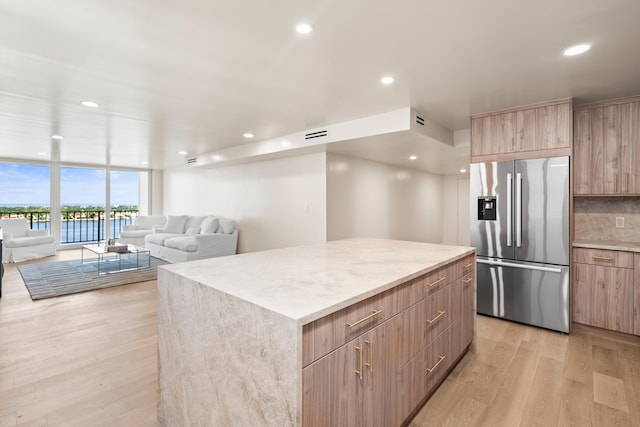 kitchen featuring light hardwood / wood-style flooring, a wall of windows, stainless steel fridge, tasteful backsplash, and a kitchen island