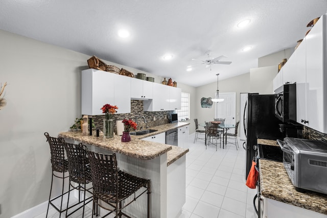 kitchen featuring white cabinetry, ceiling fan, vaulted ceiling, a breakfast bar, and appliances with stainless steel finishes