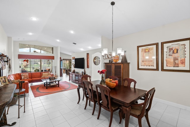 dining room featuring ceiling fan with notable chandelier, light tile patterned flooring, and vaulted ceiling