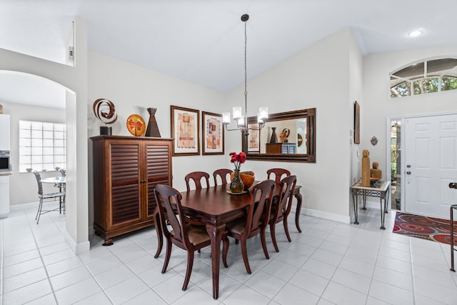 tiled dining area featuring high vaulted ceiling and an inviting chandelier