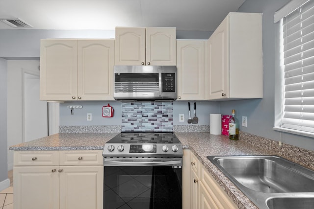 kitchen with decorative backsplash, sink, light tile patterned flooring, and stainless steel appliances