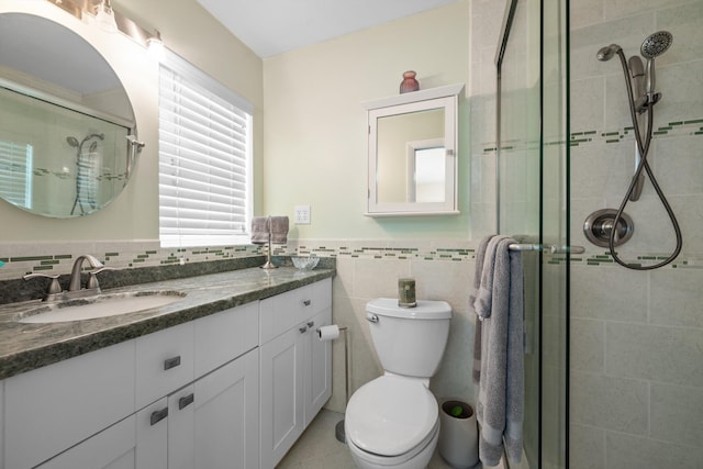 bathroom with vanity, toilet, a shower with shower door, and tile walls