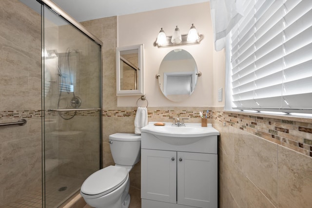 bathroom featuring vanity, a shower with door, toilet, and tile walls