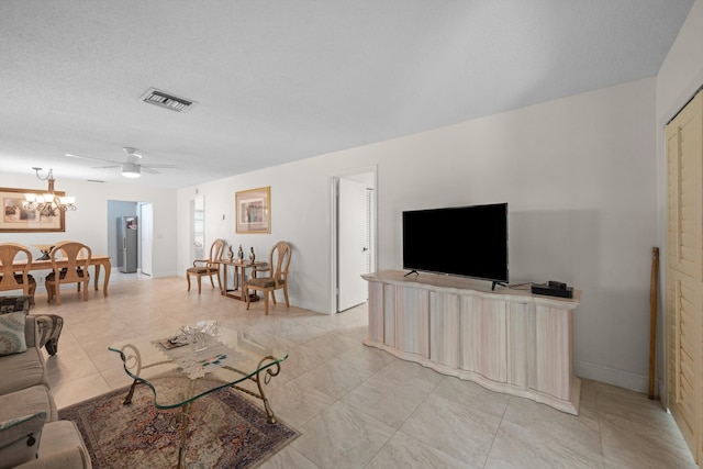 living room featuring ceiling fan with notable chandelier, a textured ceiling, and water heater