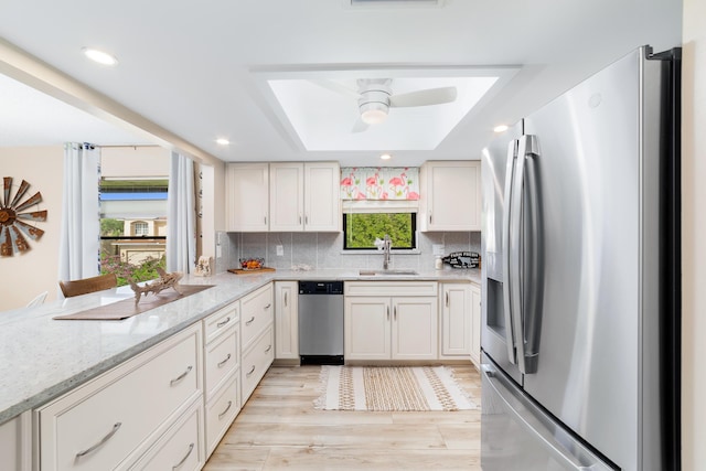 kitchen featuring a sink, a raised ceiling, decorative backsplash, and stainless steel appliances