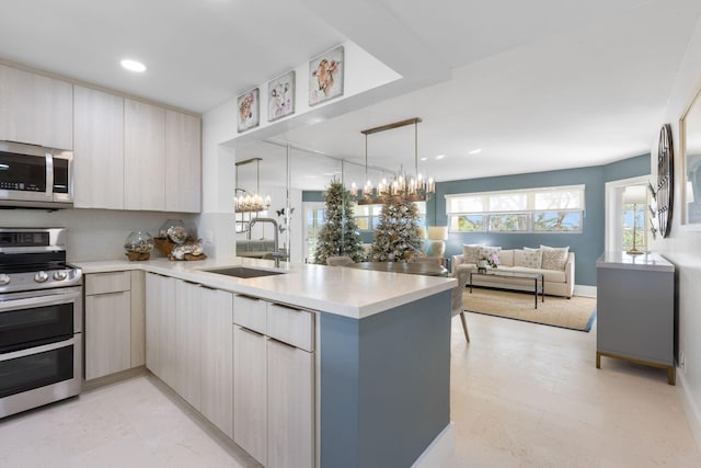 kitchen with decorative light fixtures, sink, kitchen peninsula, and stainless steel appliances