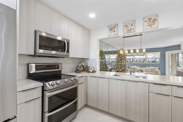 kitchen with sink, stainless steel appliances, an inviting chandelier, decorative light fixtures, and decorative backsplash