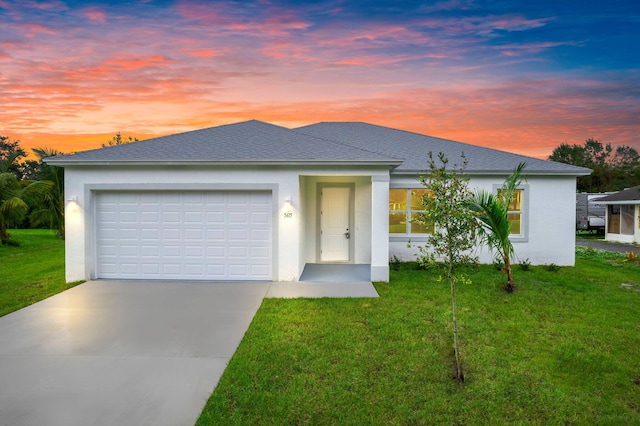 view of front facade with a front yard, an attached garage, concrete driveway, and stucco siding