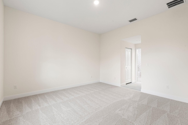 empty room featuring baseboards, visible vents, and light carpet