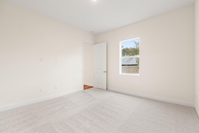 unfurnished room featuring baseboards and light colored carpet