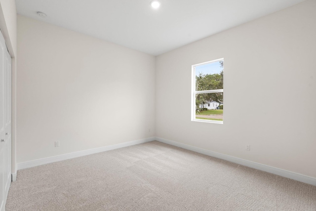 unfurnished room with light colored carpet and baseboards