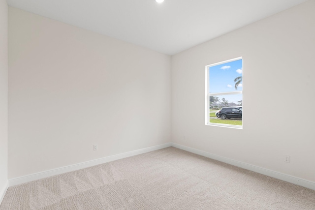 spare room with baseboards and light carpet