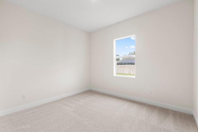 empty room featuring baseboards and light carpet