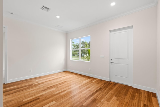 spare room with visible vents, light wood-style flooring, baseboards, and ornamental molding