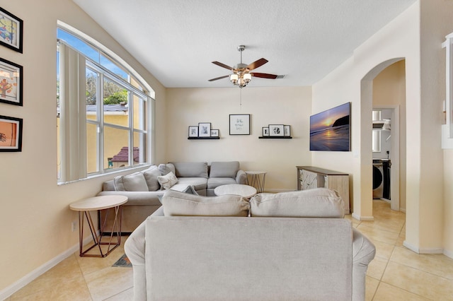 tiled living room with a textured ceiling, washer / clothes dryer, and ceiling fan