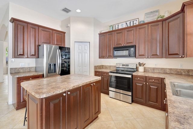 kitchen featuring light tile patterned flooring, sink, a kitchen island, and stainless steel appliances