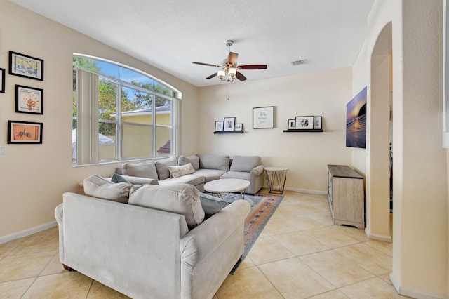 living room with ceiling fan, light tile patterned floors, and a textured ceiling